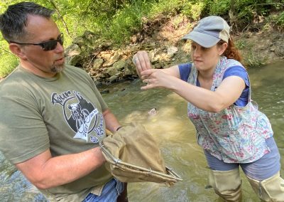 Two teachers collect water samples in stream