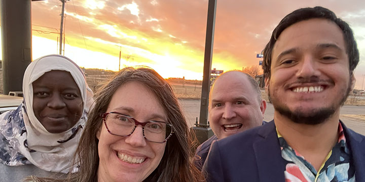 4 people pose in front of sunset